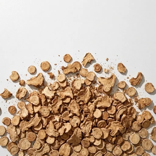 Dried galangal slices and small cut pieces arranged on a white background